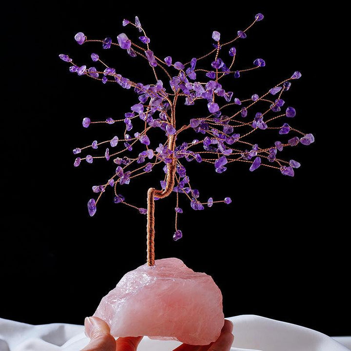 natural crystal bonsai tree with raw rose quartz base on the hand