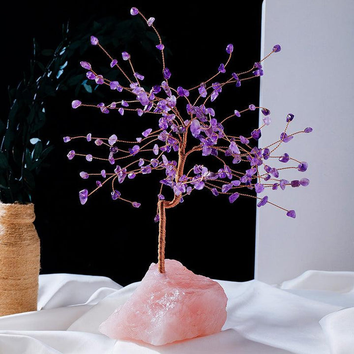natural crystal bonsai tree with raw rose quartz base on the table